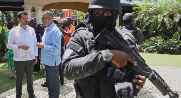 Le guardie di sicurezza guardano il Primo Ministro di Haiti, Alix Didier Son-Aime, al centro, parla con l'accusa del Messico, Jesus Cisneros, dopo aver partecipato a un evento significativo un anno dall'inizio della missione di sostegno alla sicurezza multinazionale a Port-Au-Prince, Haiti giovedì.